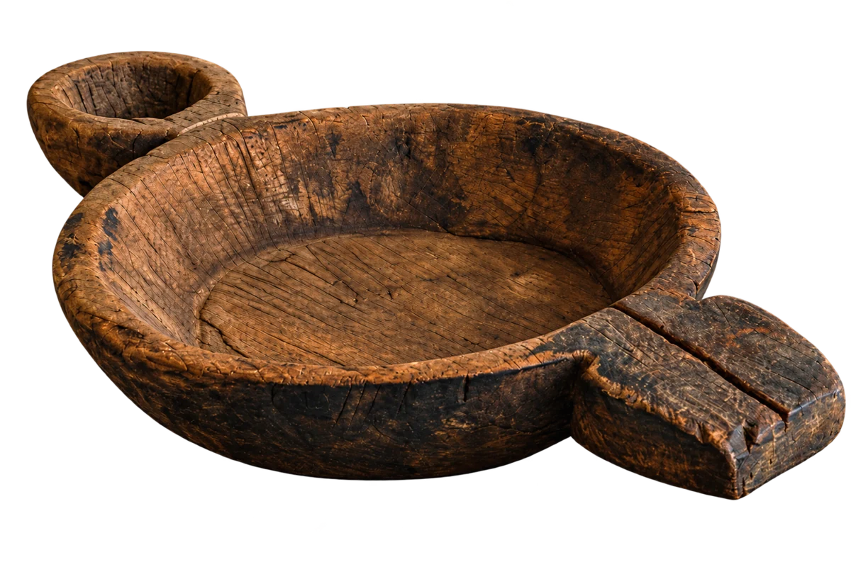 An old wooden bowl beside a fire